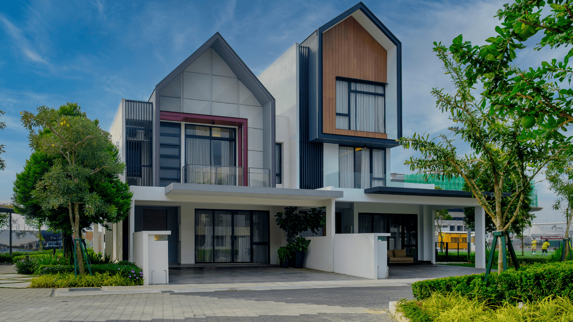 Front view of a modern duplex with two-storey design, landscaped garden, glass balcony and contemporary facade